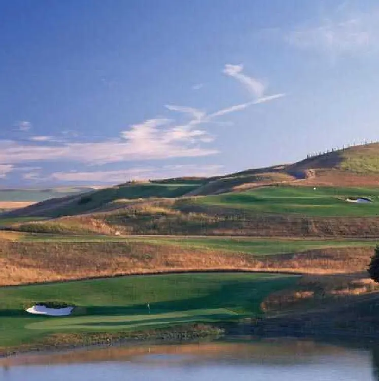 A golf course with green and blue water.