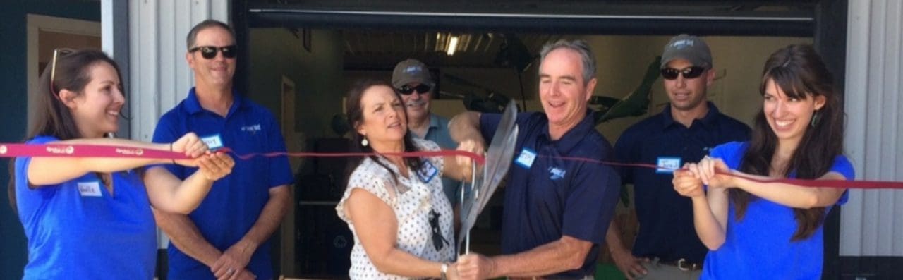 A woman and man cutting the ribbon to open a new business.